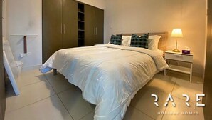 A bedroom with a bed, a nightstand, a wardrobe, and a ceiling light. - Stylish 1 Bed apartment in Downtown Dubai (Dubai)