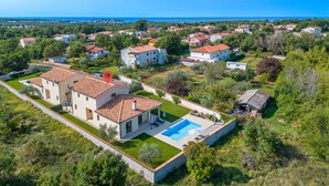 A residential area with houses, a swimming pool, and a view of the sea.