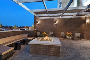 An outdoor patio with a fire pit, seating, and a brick wall. - SpringHill Suites by Marriott Dallas Richardson/University Area (Dallas)