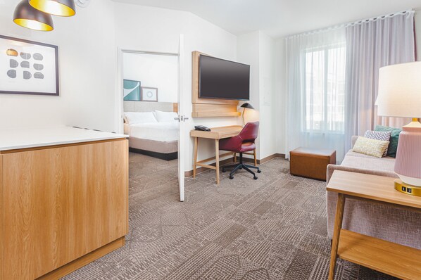 Una habitación de hotel con cama, escritorio con silla, televisor y lámpara.
