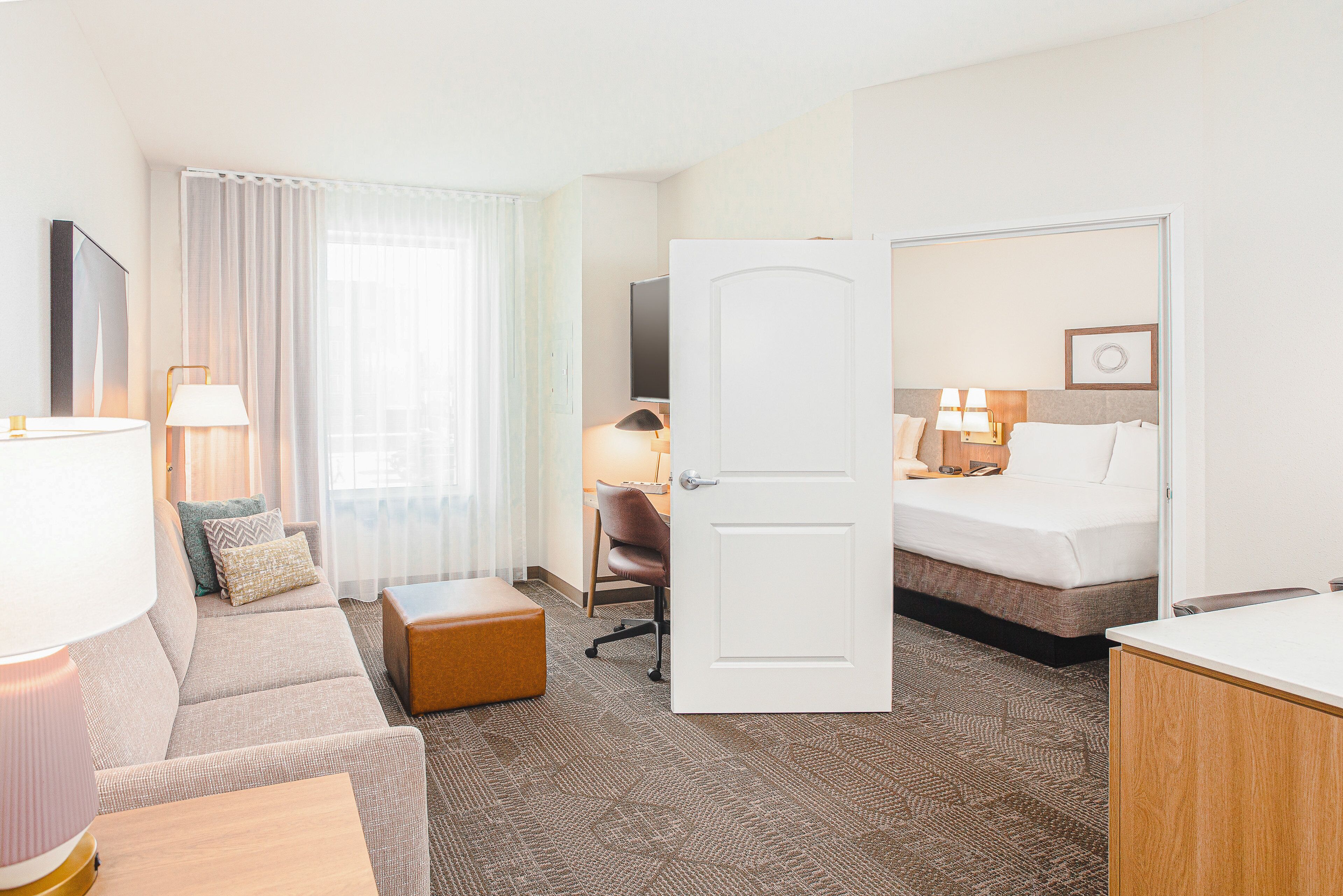Ein Hotelzimmer mit Bett, einer Couch, einem Schreibtisch und einem Sessel.