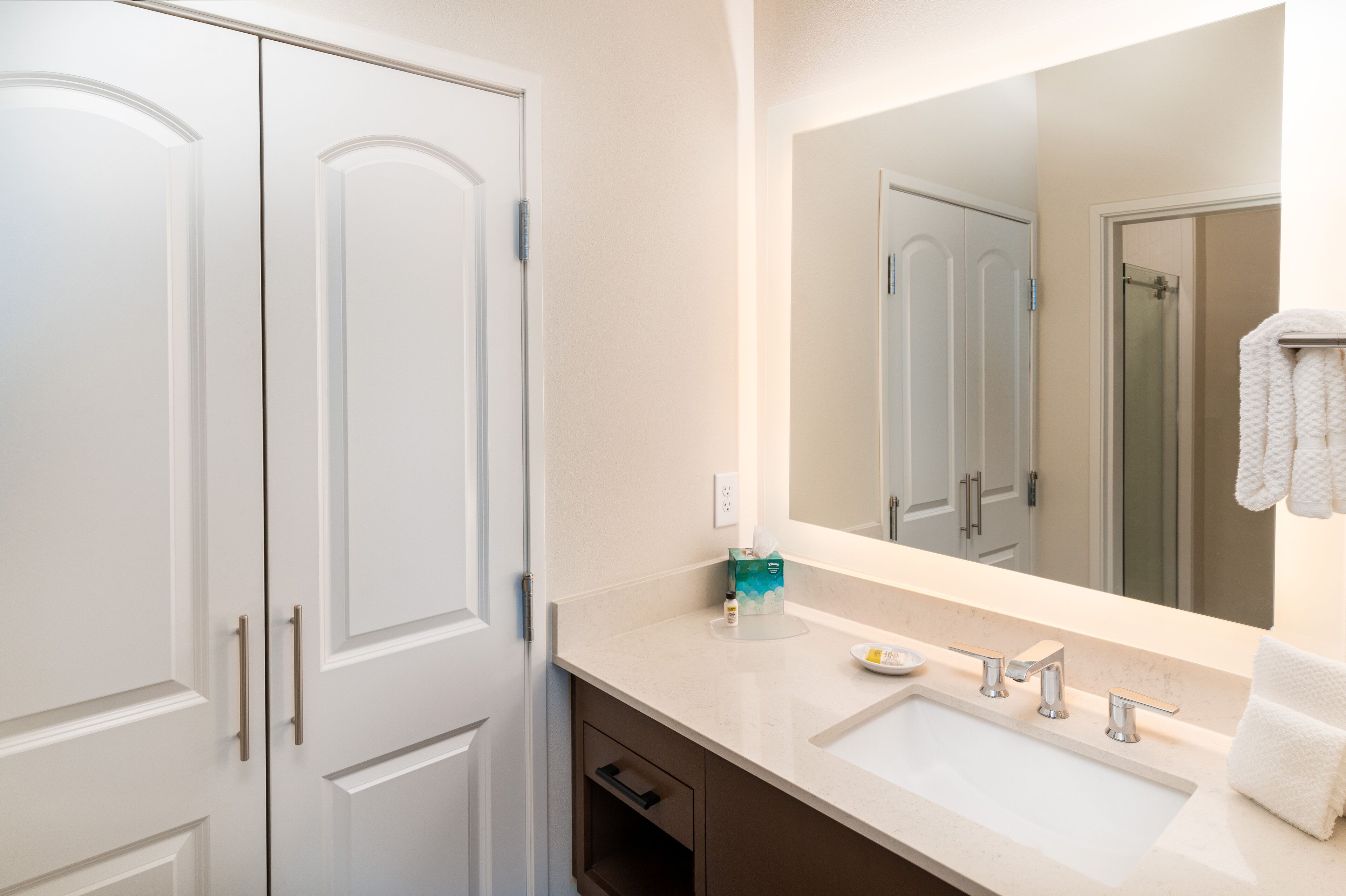 A bathroom with a white sink, two towel racks, and a large mirror.