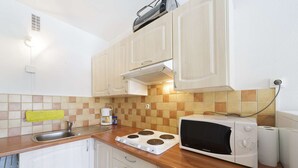 A kitchen with white cabinets, a microwave, a toaster, and a sink.