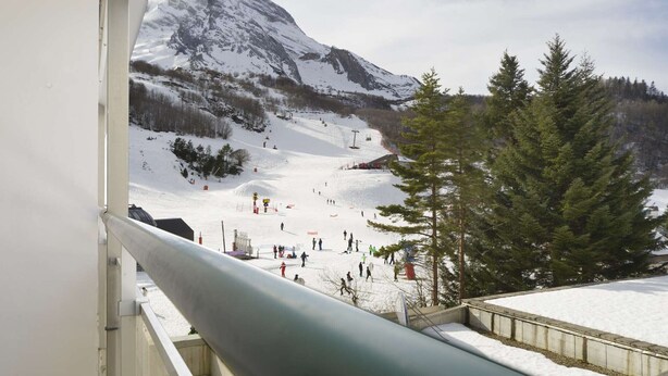A snow-covered mountain landscape with a ski slope and a few skiers.