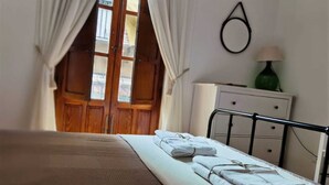 Una camera da letto con un letto, un comodino con una lampada, una cassettiera e una finestra con tende.