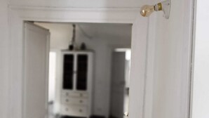 Una porta che dà su una stanza con un armadietto bianco e un lampadario.