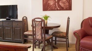 Een eetruimte met een tafel, stoelen, een televisie en een kast.
