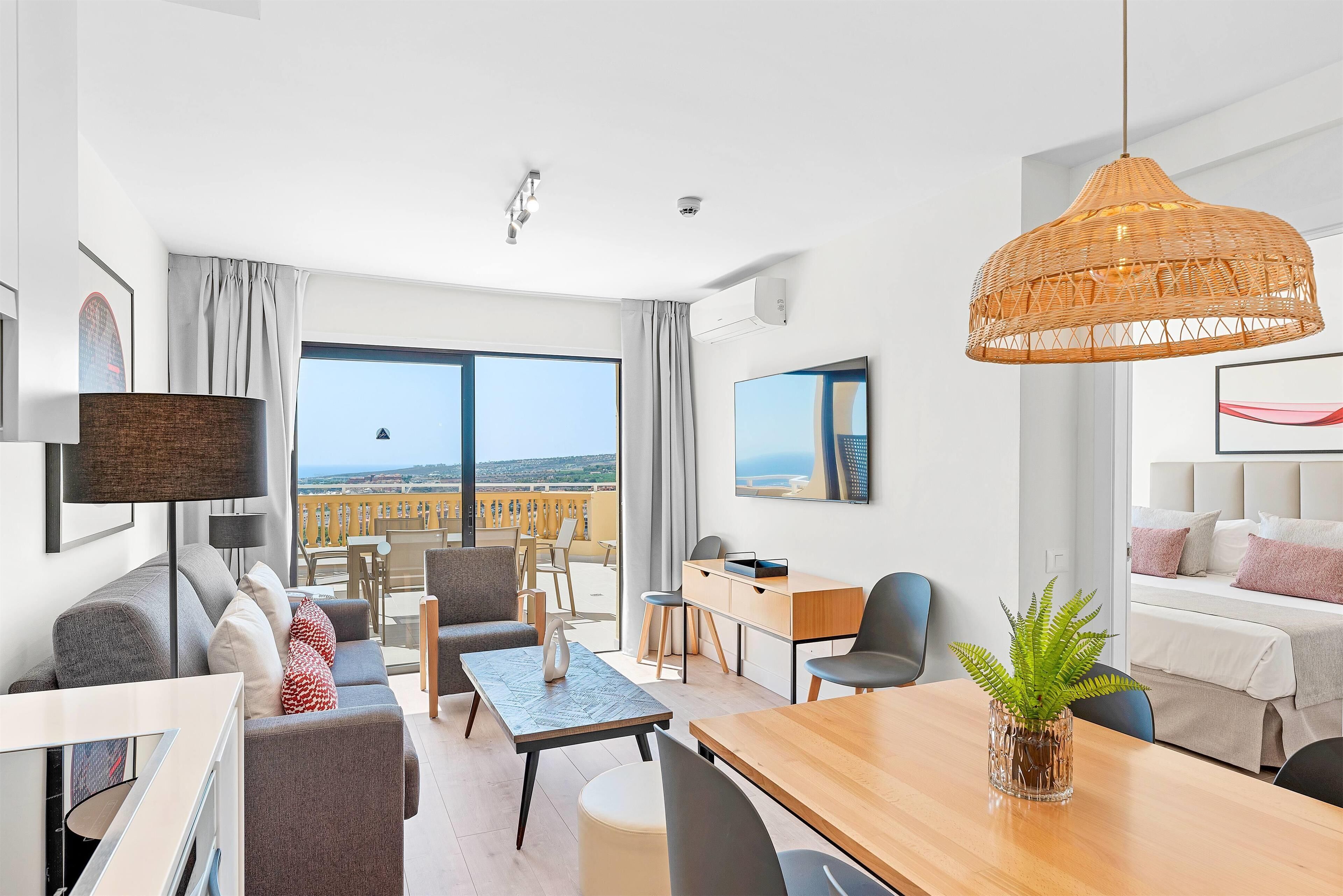 Een moderne hotelkamer met balkon, een eethoek en een zithoek.