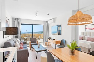Una habitación de hotel moderna con balcón, zona de comedor y sala de estar.