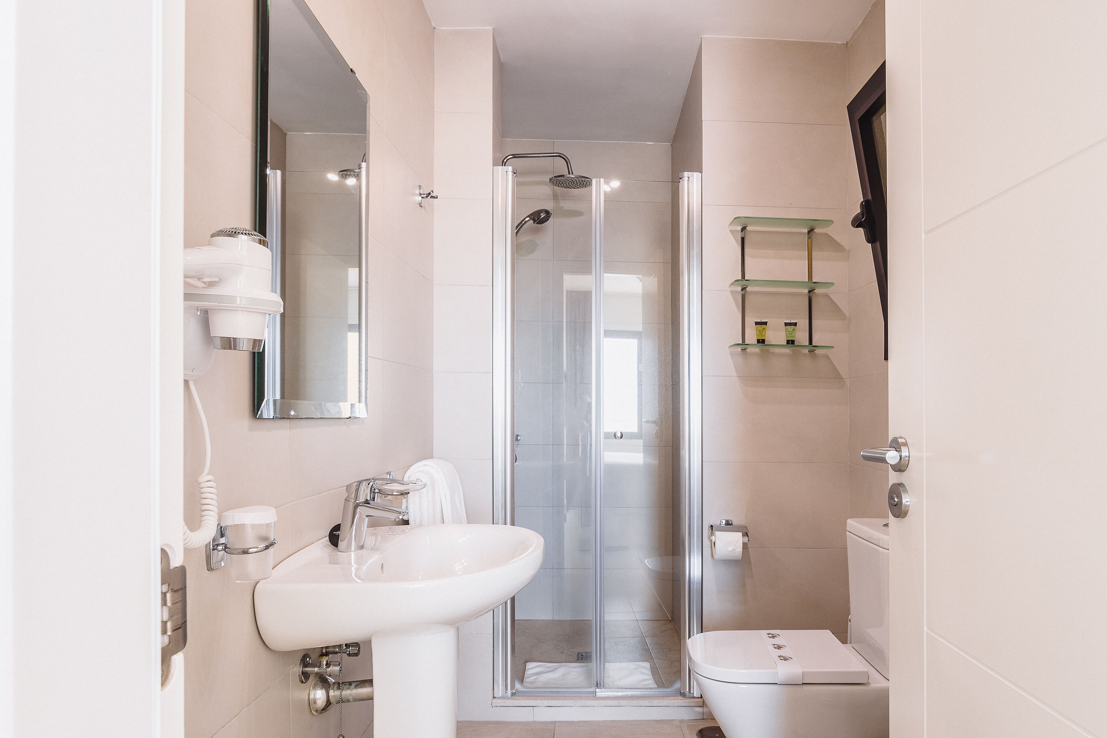 Un baño moderno con ducha de vidrio, lavamanos blanco y retrete.