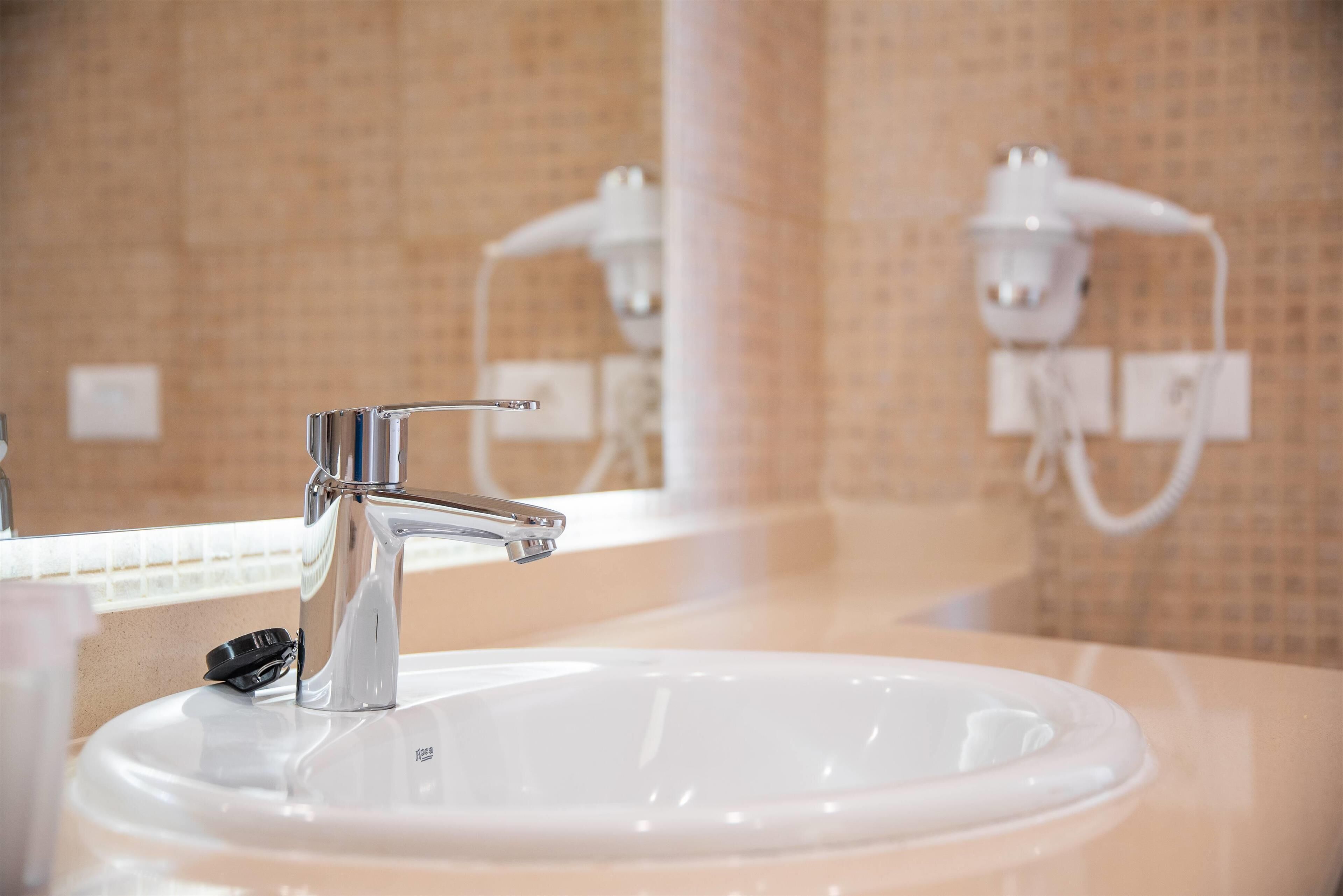 Un lavabo de salle de bain avec un robinet moderne, un miroir et un porte-serviettes.