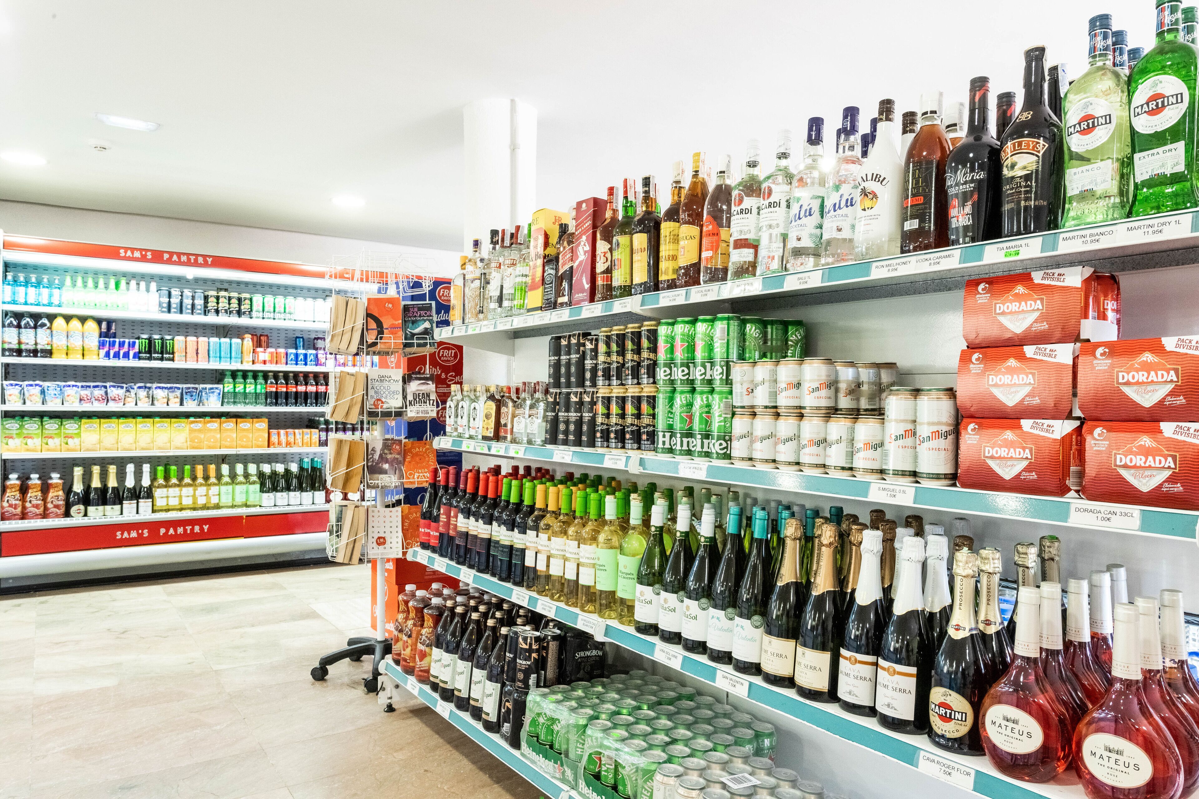 En købmand med hylder fyldt med forskellige flasker og dåser alkohol.