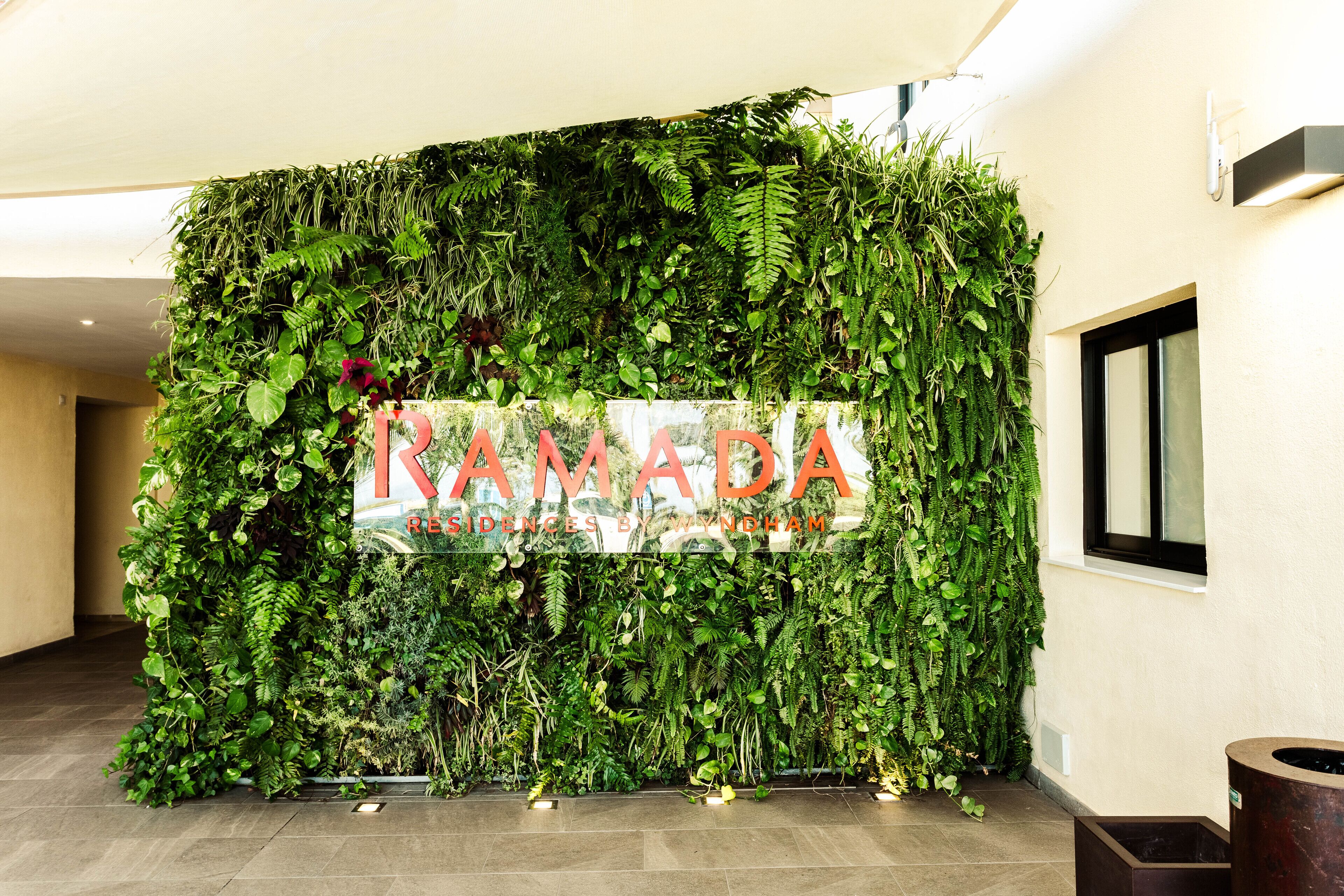 Un espace d’accueil avec un mur recouvert de verdure et une enseigne indiquant « RÉSIDENCES NAMADA, PAR WYNGHAM ».