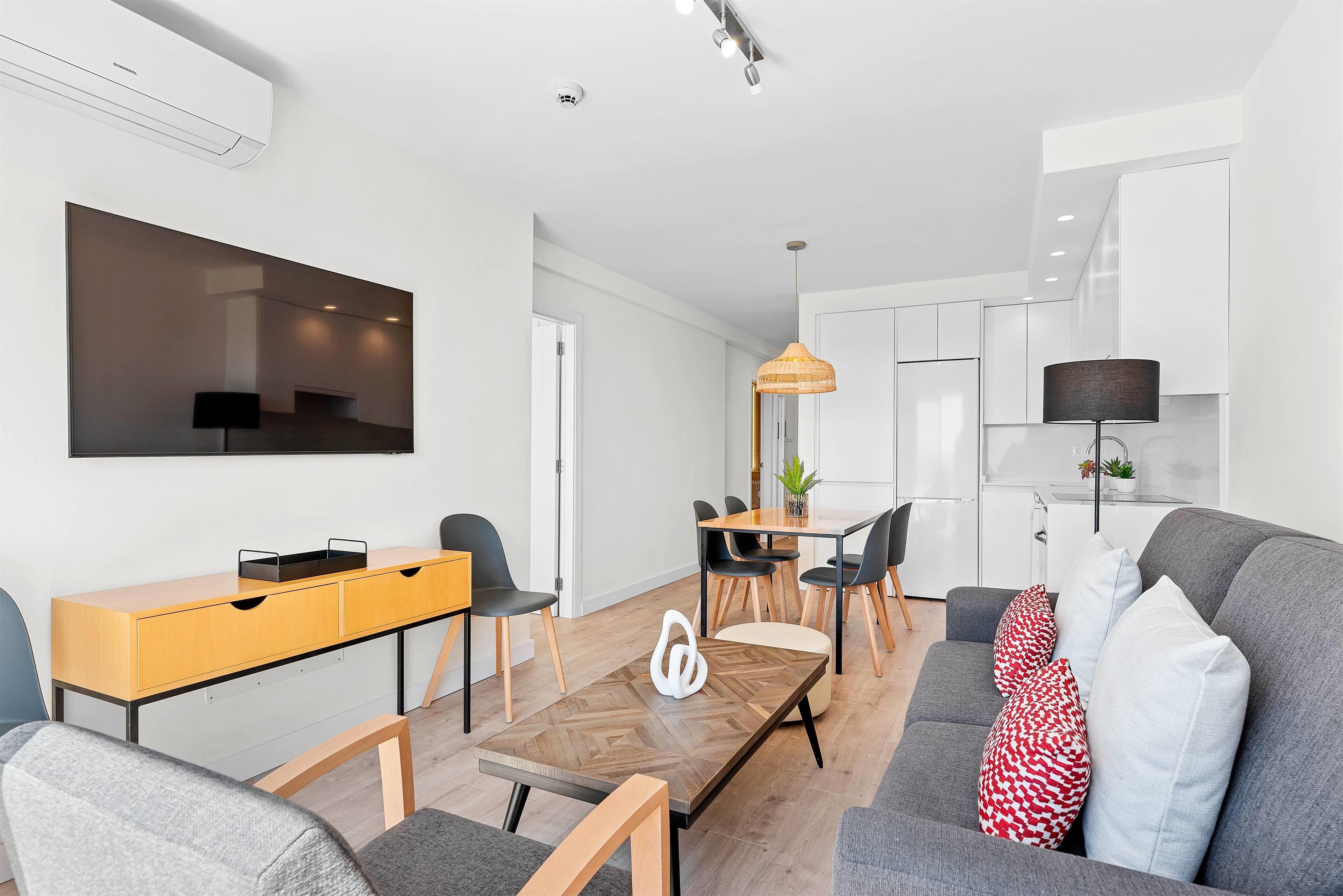 A modern living room with a sofa, a coffee table, and a dining area with chairs and a table.