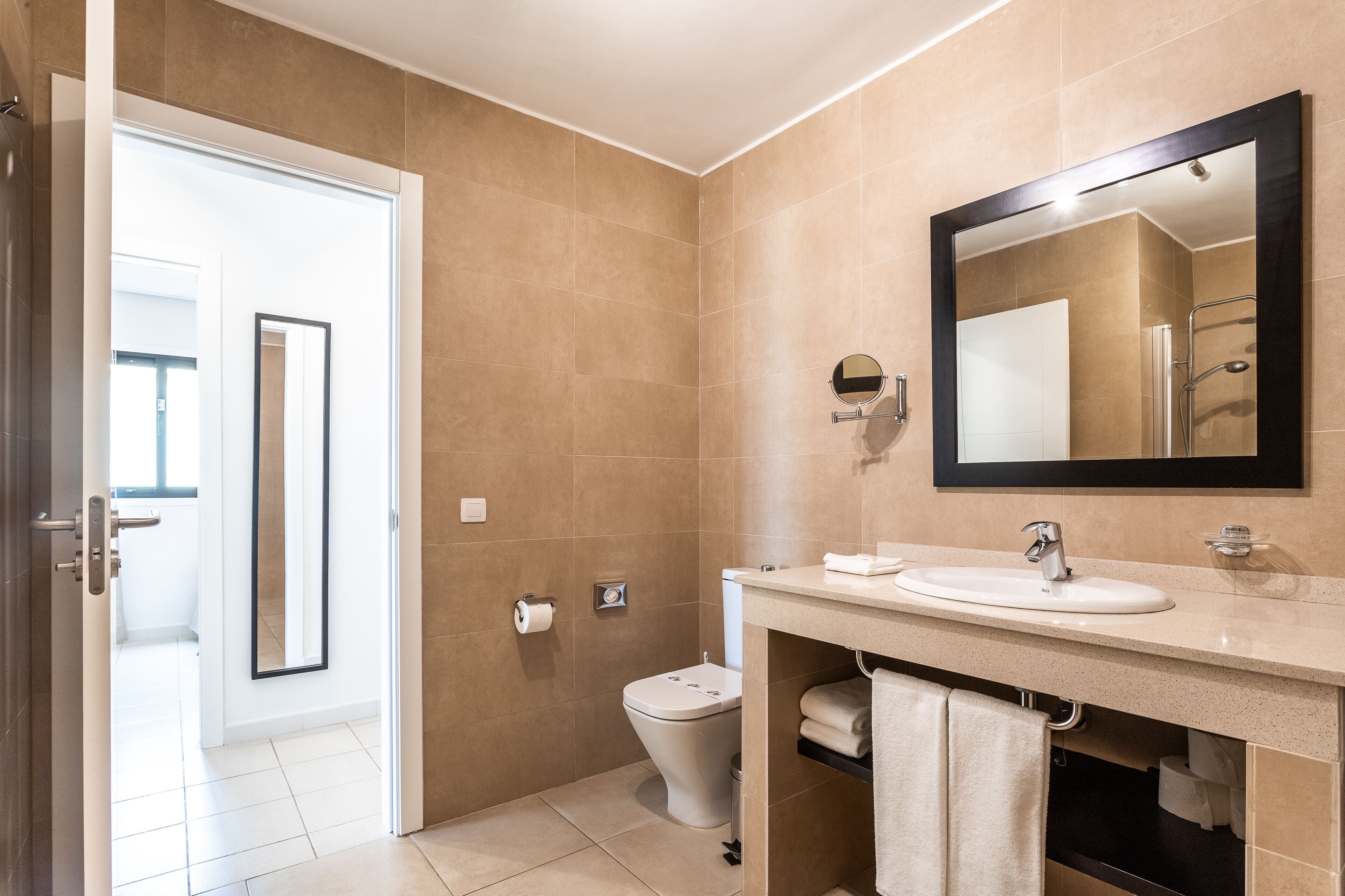 A modern bathroom with a toilet, sink, and mirror.