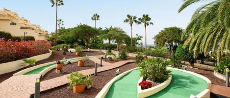 A landscaped area with a winding path, palm trees, and potted plants.