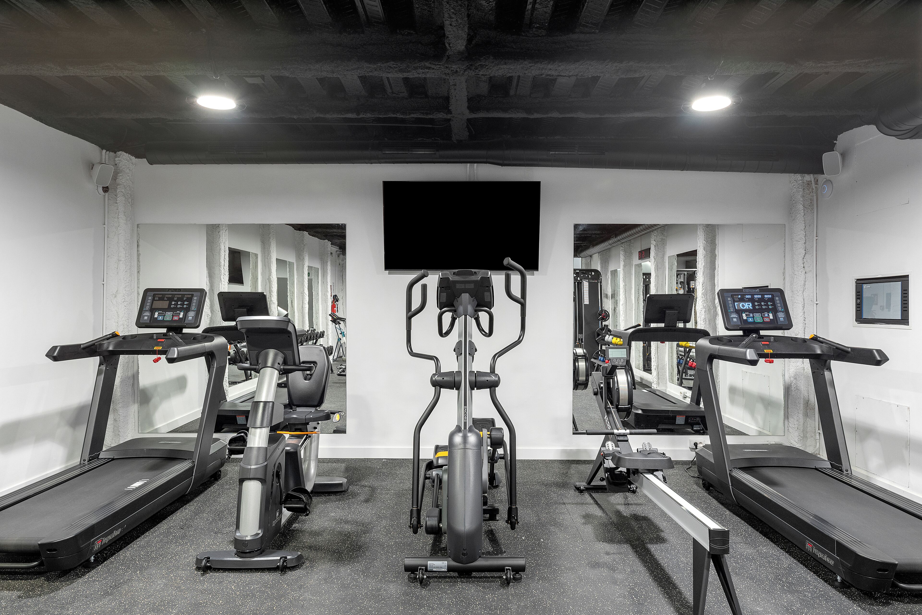 Een fitnessruimte met loopbanden, elliptische trainers en een hometrainer.