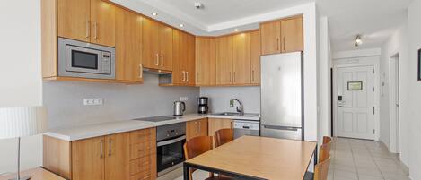 Una cocina moderna con armarios de madera, electrodomésticos de acero inoxidable y una zona de comedor con mesa y sillas.