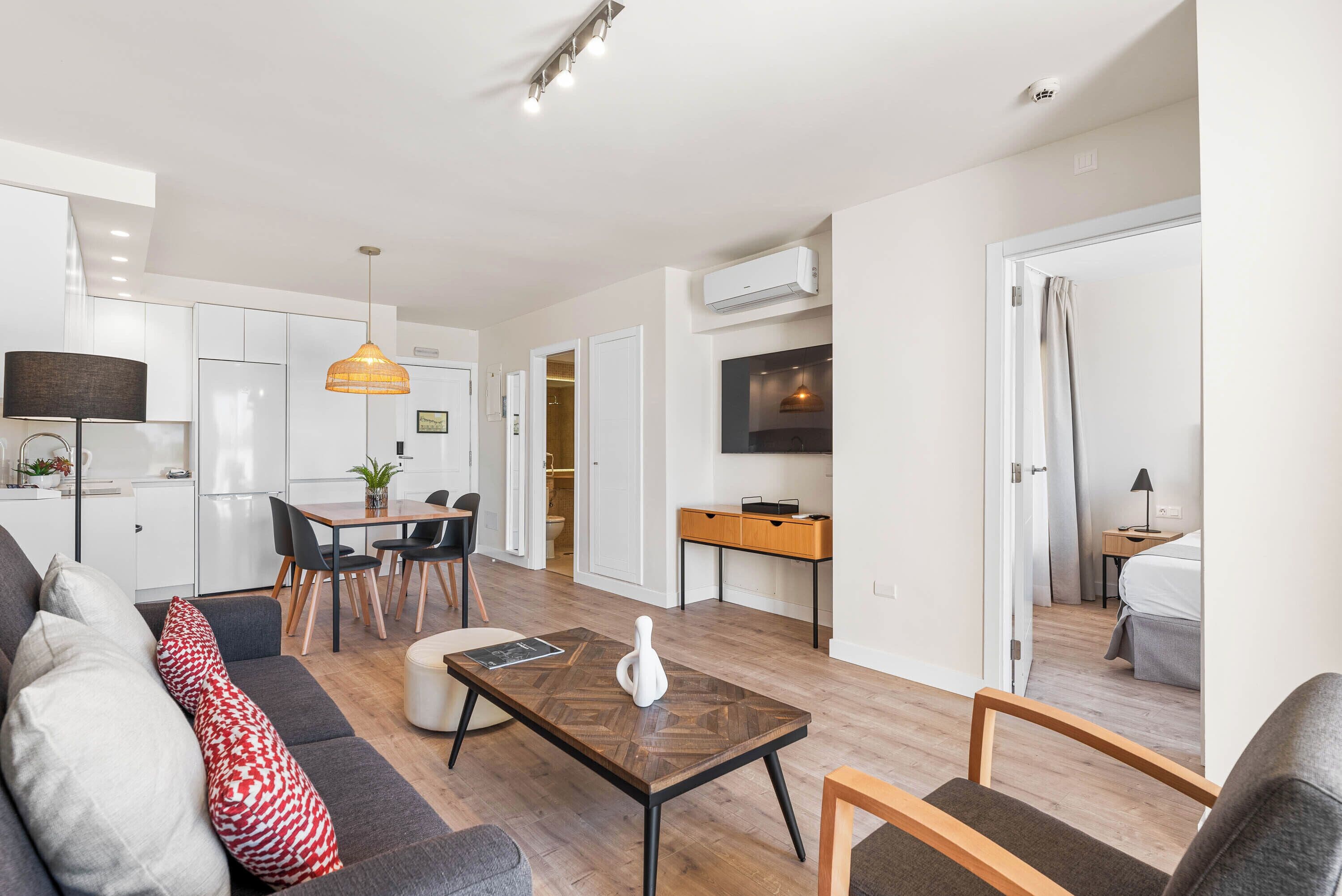 A modern apartment with a dining area, kitchen, and living space.