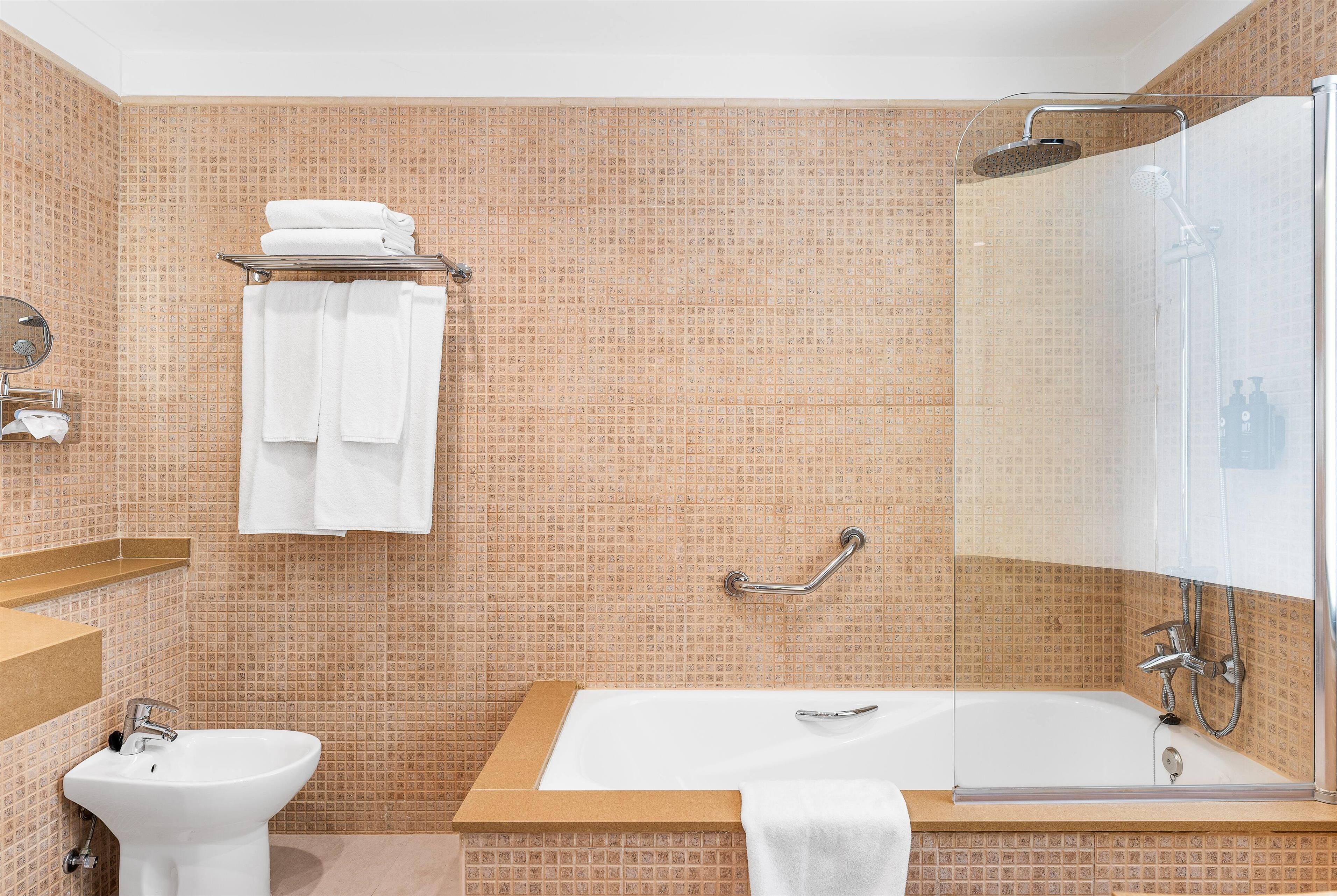 A bathroom with a bathtub, a sink, a shower, and a handrail.