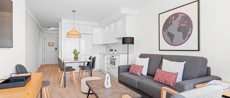 A modern living room with a grey sofa, wooden coffee table, and a dining area with a table and chairs.