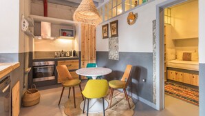 Een compacte keuken met moderne apparaten, een eetgedeelte met een ronde tafel en stoelen, en een gezellig slaapgedeelte met een bed en opbergruimte.