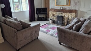 A living room with two sofas, a fireplace, a television, and a large mirror. - Well appointed cottage on a working hill farm (Otley)