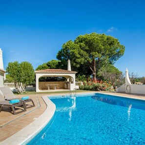 Relax by the serene pool surrounded by lounge chairs and a shaded seating area.