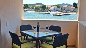 Een balkon met een tafel en stoelen, met uitzicht op water en gebouwen.