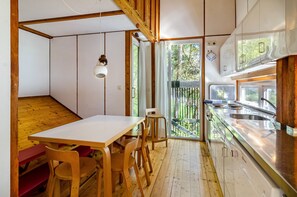 A kitchen with a wooden table and chairs, a stainless steel sink, and a sliding glass door leading to a balcony.