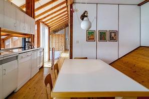 A kitchen with white cabinets, a wooden dining table, and a hanging light fixture.