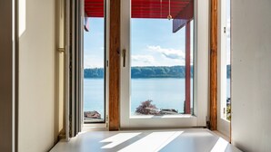 A room with a view of a lake, a wooden door, and a white wall. - Holiday Home "Adlerhorst Über Dem Bodensee" with Panoramic Glazing, Terrace and Lake View (Sipplingen)