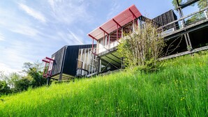 A modern building with a flat roof, large windows, and a red and black color scheme. - Holiday Home "Adlerhorst Über Dem Bodensee" with Panoramic Glazing, Terrace and Lake View (Sipplingen)