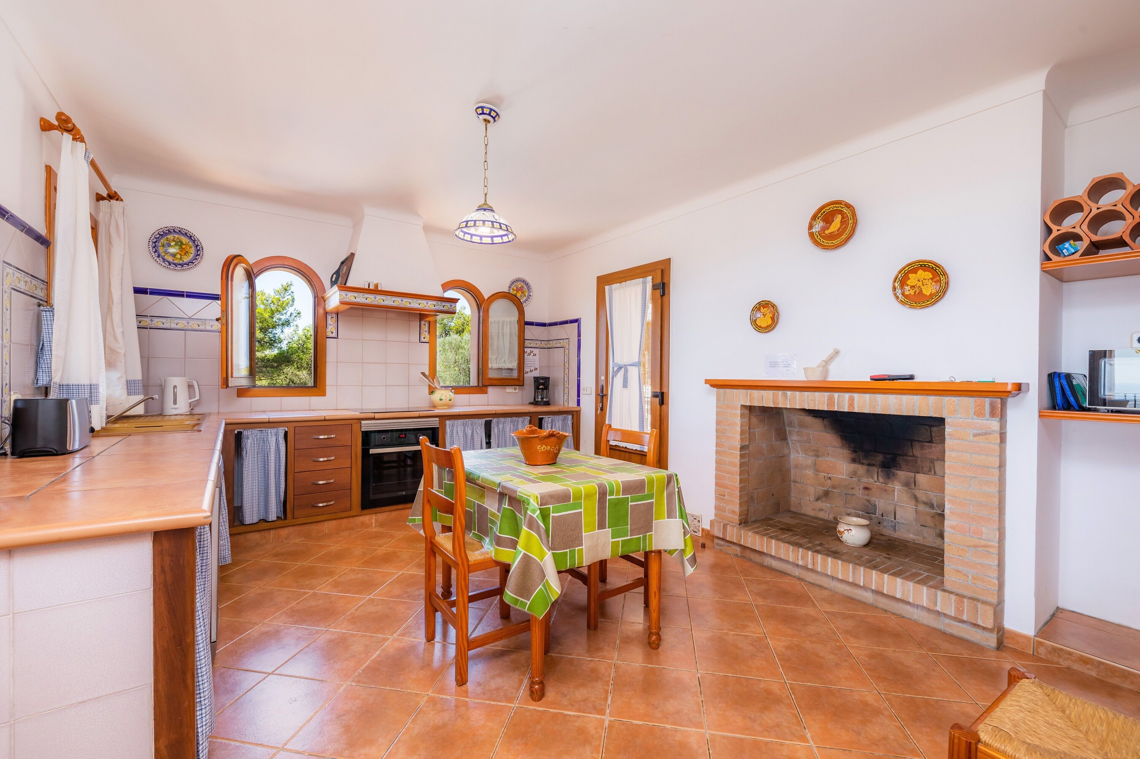 A kitchen with a dining table, chairs, a fireplace, and a view of the outdoors.