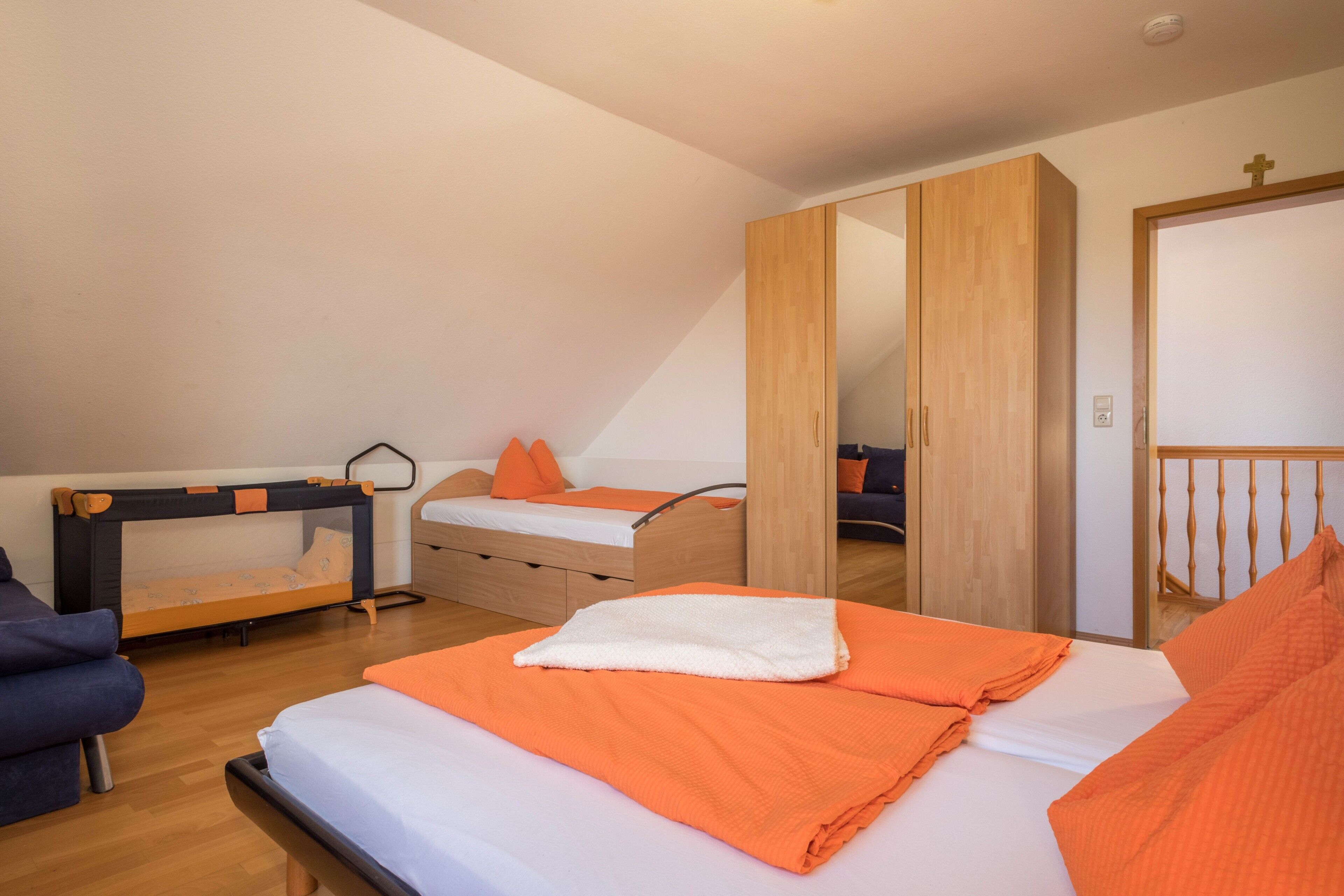 Un dormitorio con una litera, una cama individual, un armario y una puerta con el símbolo de la cruz.
