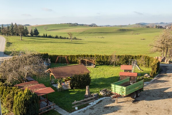 A rural landscape with a green truck, a wooden structure, and a fenced area.