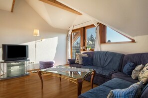 A living room with a TV, sofa, and glass coffee table.