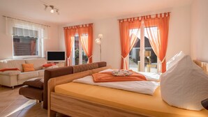 Un dormitorio con cama, sofá, televisor y cortinas.