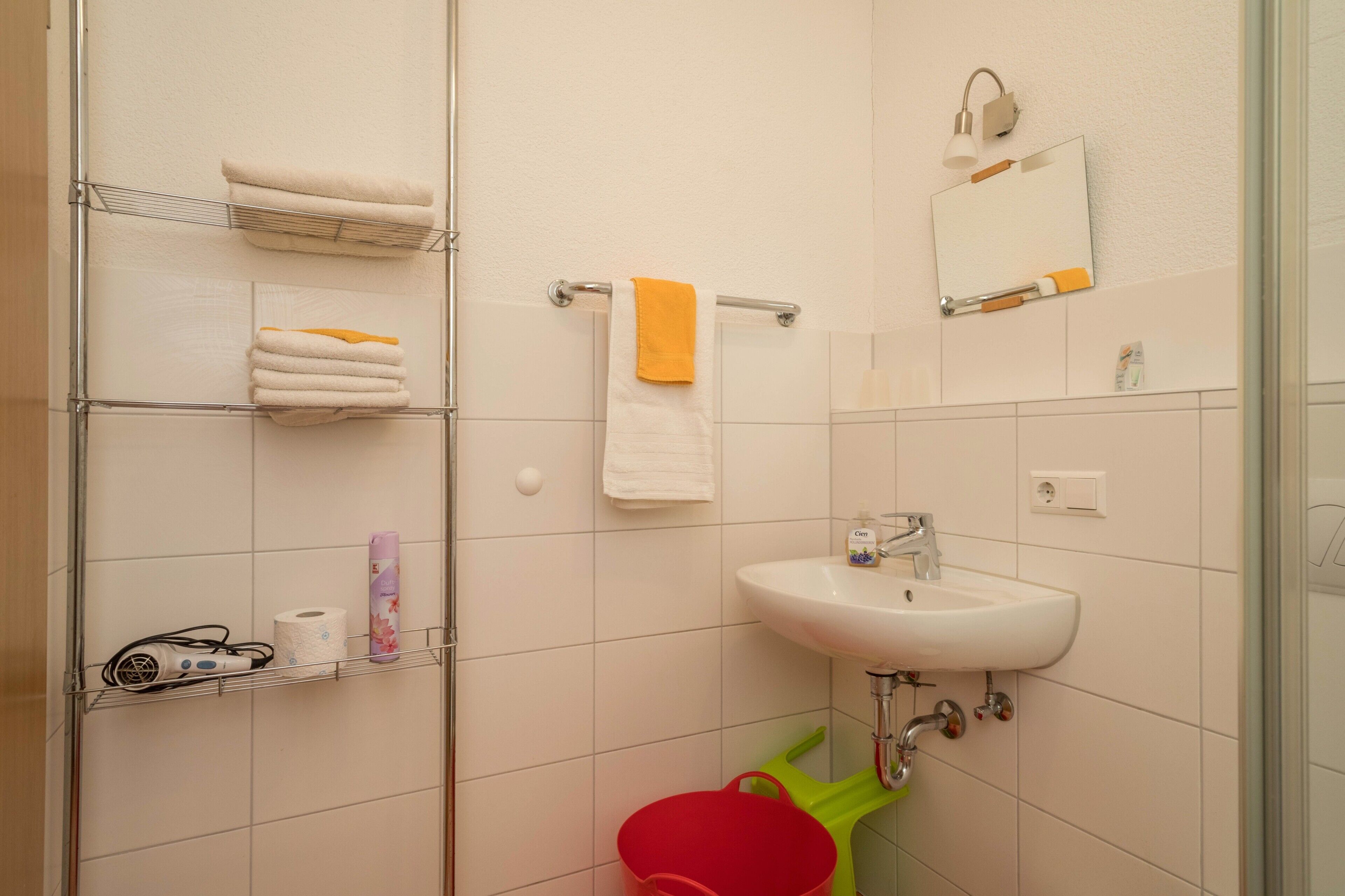 Ein Badezimmer mit Waschbecken, Spiegel, Handtuchhalter und Duschbereich.