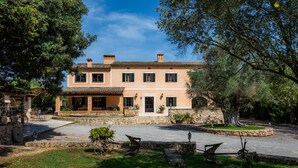 Una casa de dos pisos con fachada de piedra, varias ventanas y un camino de entrada pavimentado.