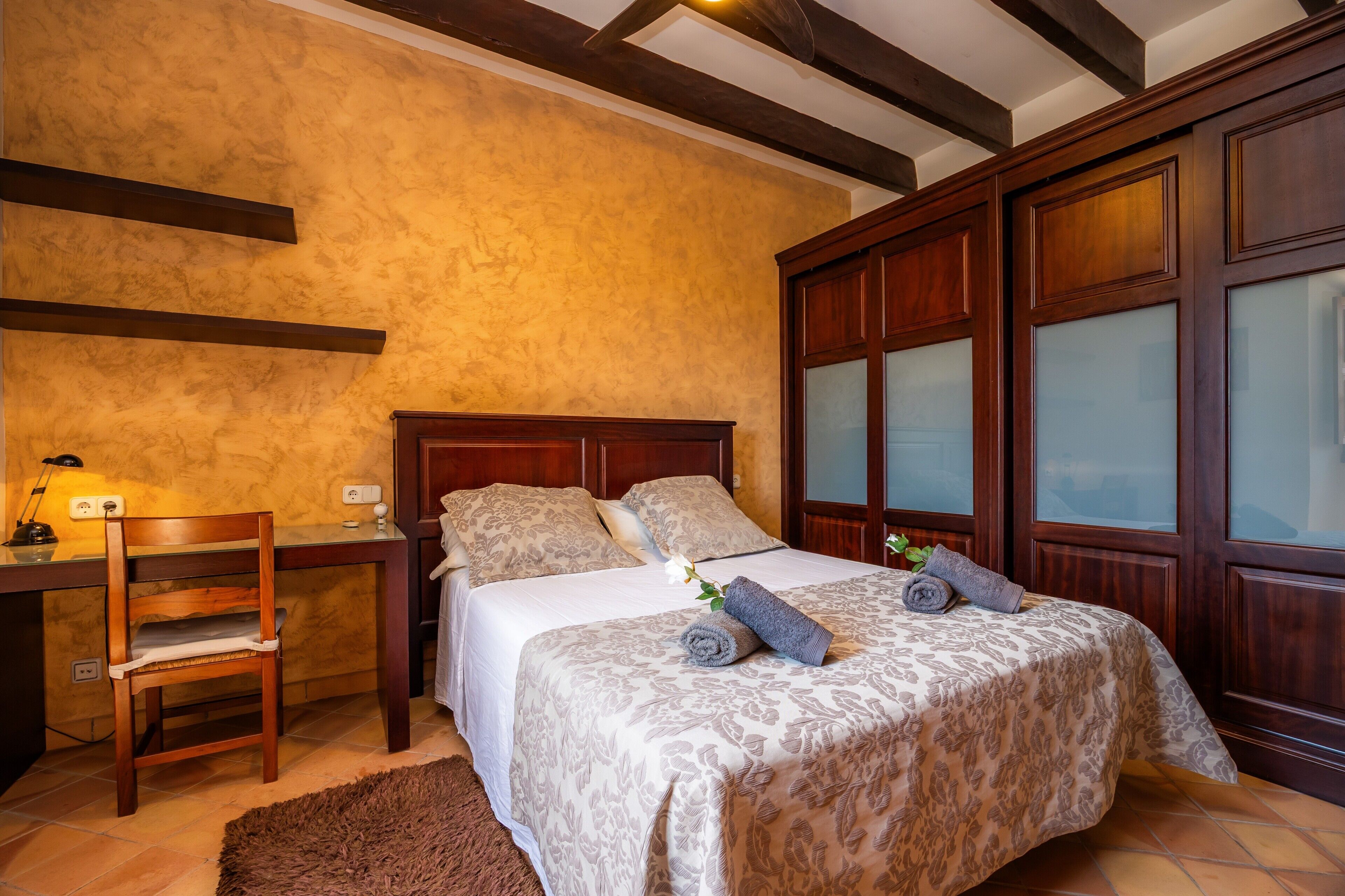 A bedroom with a wooden bed, a desk, and a chair.