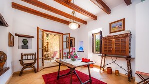 Una habitación con una mesa de madera, una alfombra roja, un armario de madera y un techo con vigas a la vista.