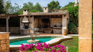 Un edificio de piedra con piscina, mobiliario exterior y zona de barbacoa.