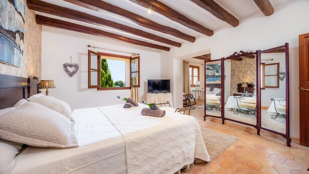 Un dormitorio con cama, televisor, espejo y vistas al exterior.