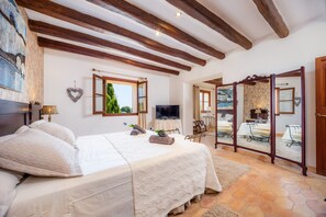 Quarto com cama, televisão, espelho e vista para o exterior.
