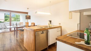 A modern kitchen with wooden countertops, a dishwasher, and a dining area with a table and chairs. - Comfortable Holiday Apartment "Felix" with Balcony, Wi-Fi & TV (Bregenz)