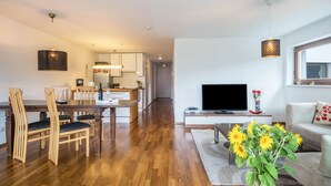 A modern living room with a wooden dining table, a flat-screen TV, and a sofa. - Comfortable Holiday Apartment "Felix" with Balcony, Wi-Fi & TV (Bregenz)