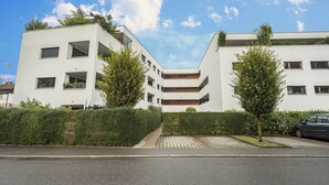 A modern building with a flat roof, multiple windows, and a paved entrance area. - Comfortable Holiday Apartment "Felix" with Balcony, Wi-Fi & TV (Bregenz)