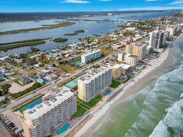 An aerial view of a coastal residential area with high-rise buildings, a beach, and a marina.
