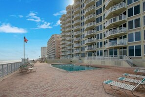 A hotel with a swimming pool, outdoor seating, and a view of the beach.